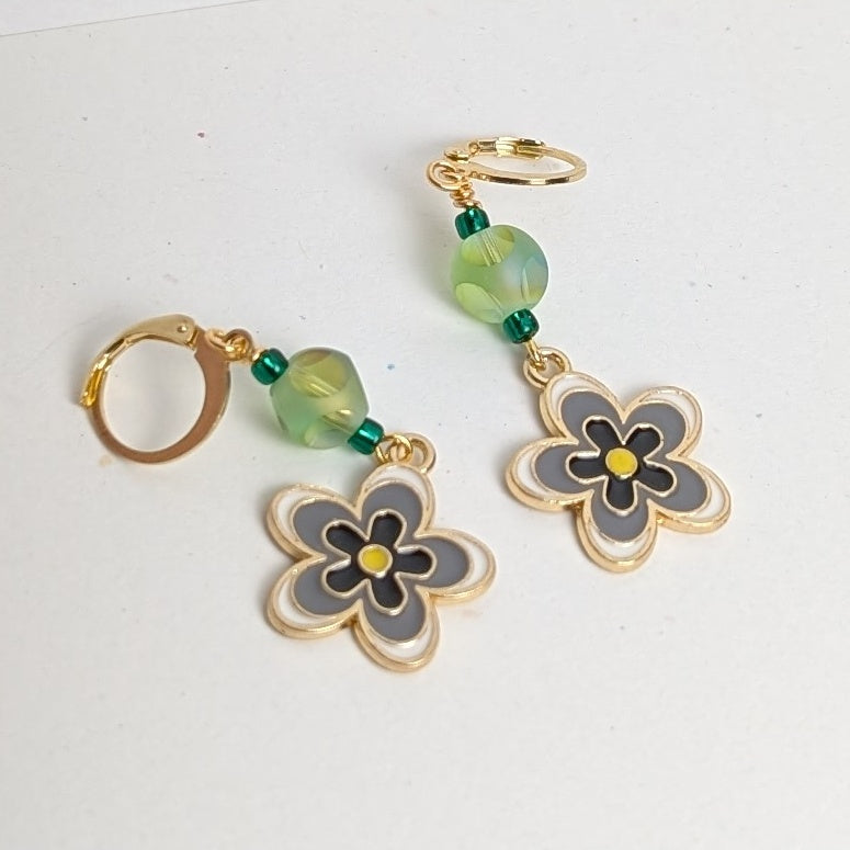 Flower-shaped earrings with green beads on a white background