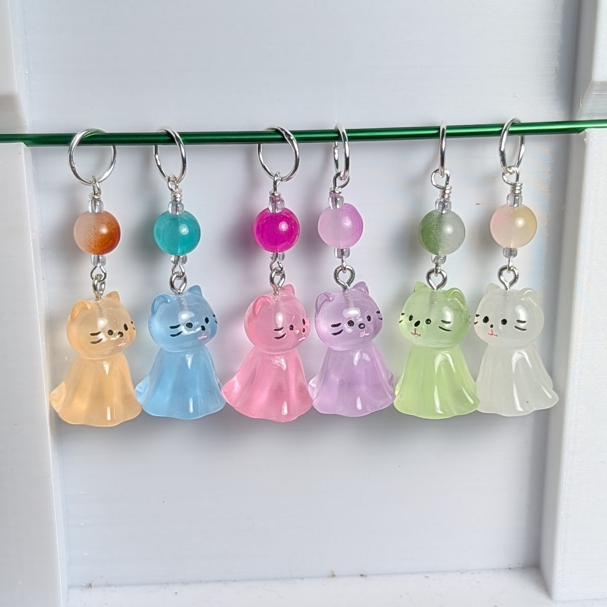 Set of colorful cat-shaped charms with beads on a white background