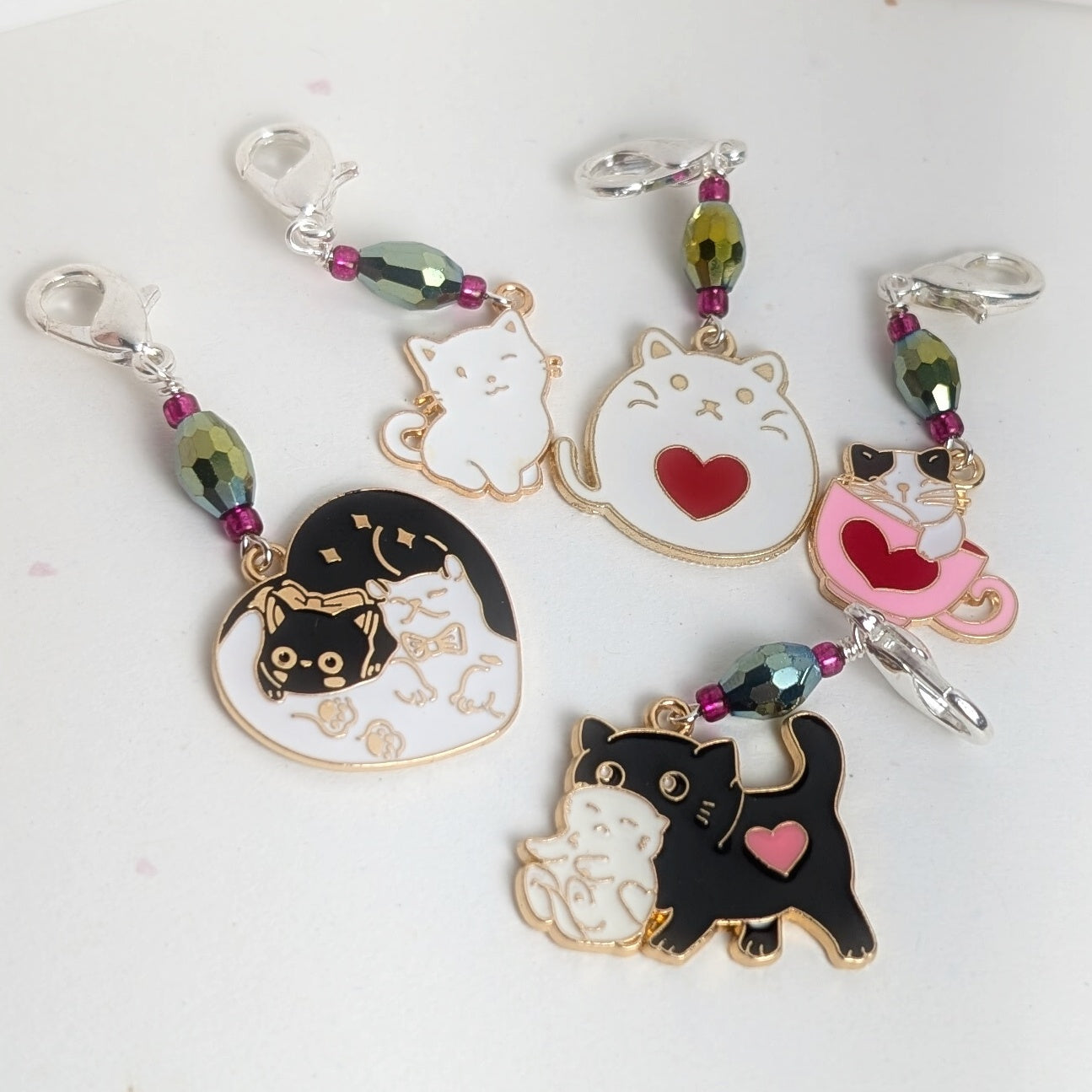 Set of cat-themed stitch markers with heart designs on a light background