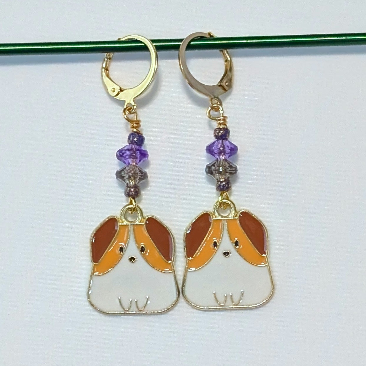Dog-shaped earrings with purple beads on a white background