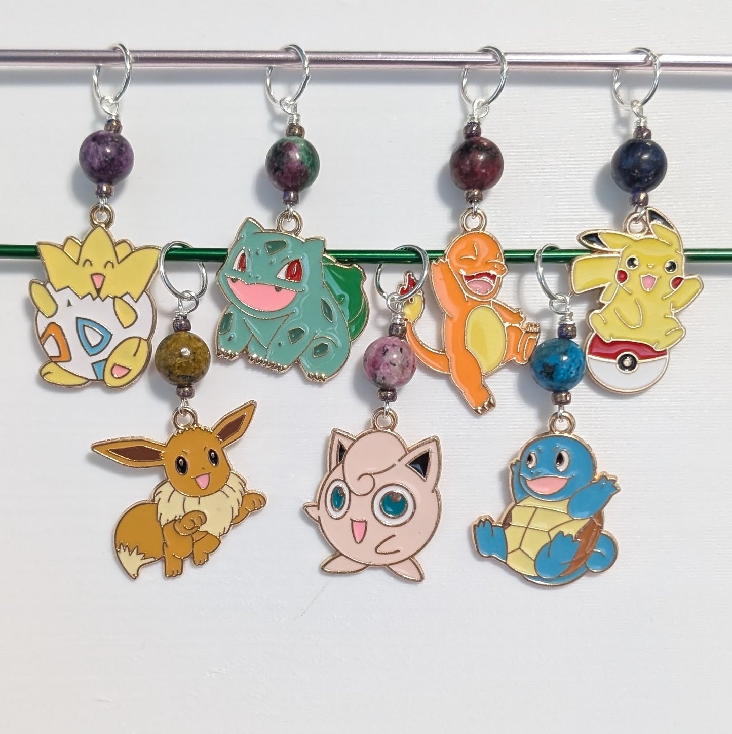 Set of colorful Pokémon stitch markers hanging on a rod.