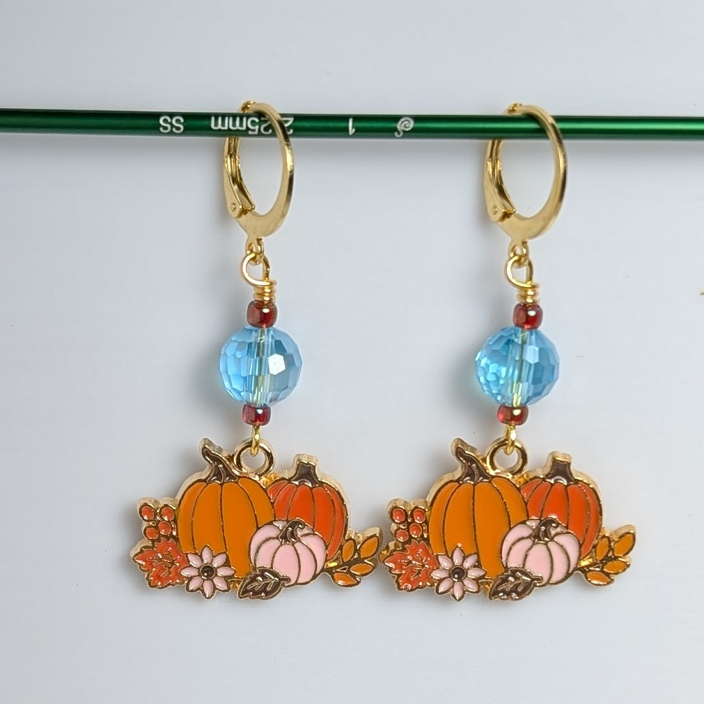 Pumpkin-shaped earrings with blue beads on a white background
