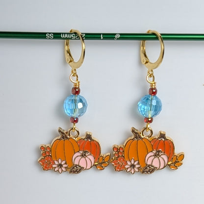 Pumpkin-shaped earrings with blue beads on a white background