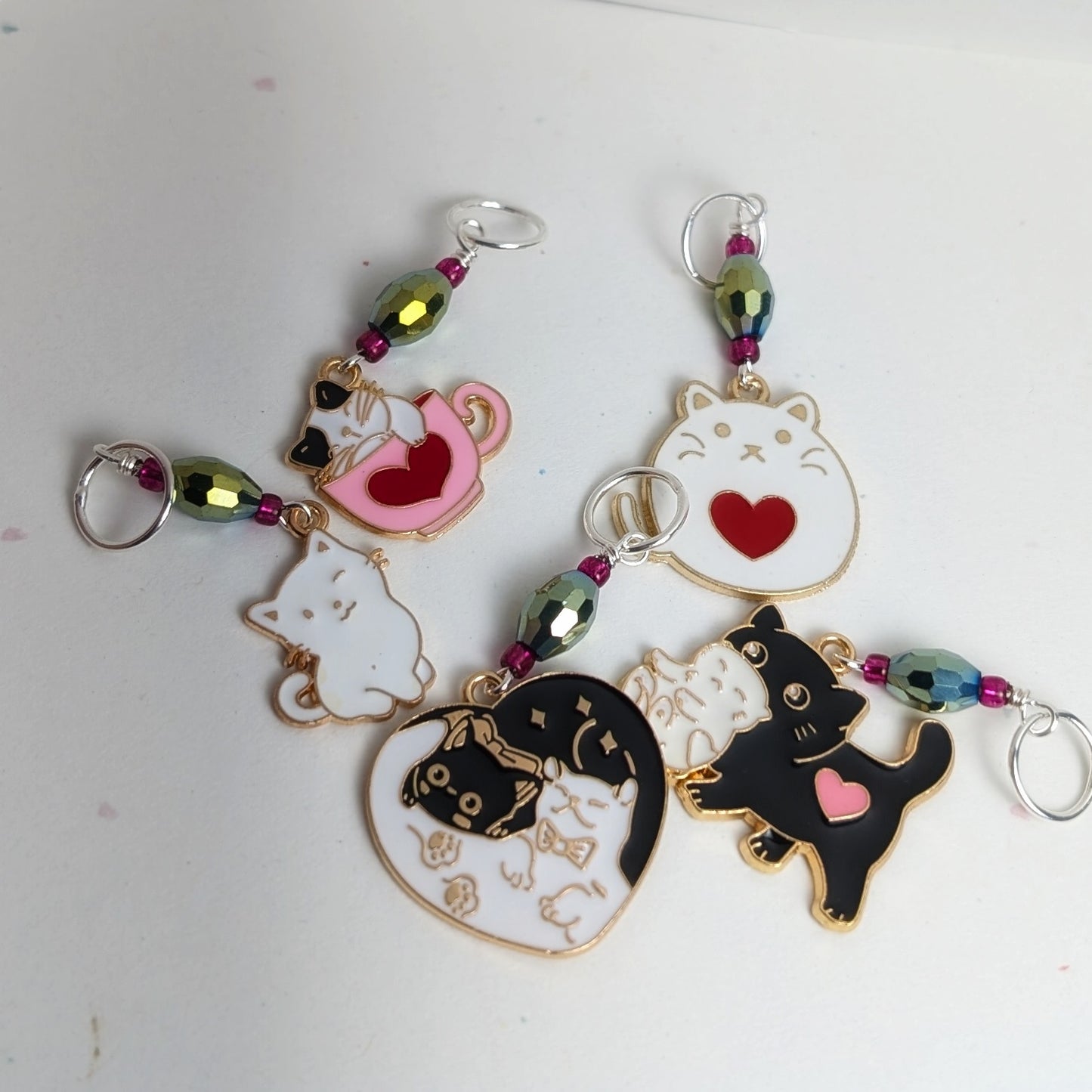 Cat-themed stitch markers with colorful beads on a white background