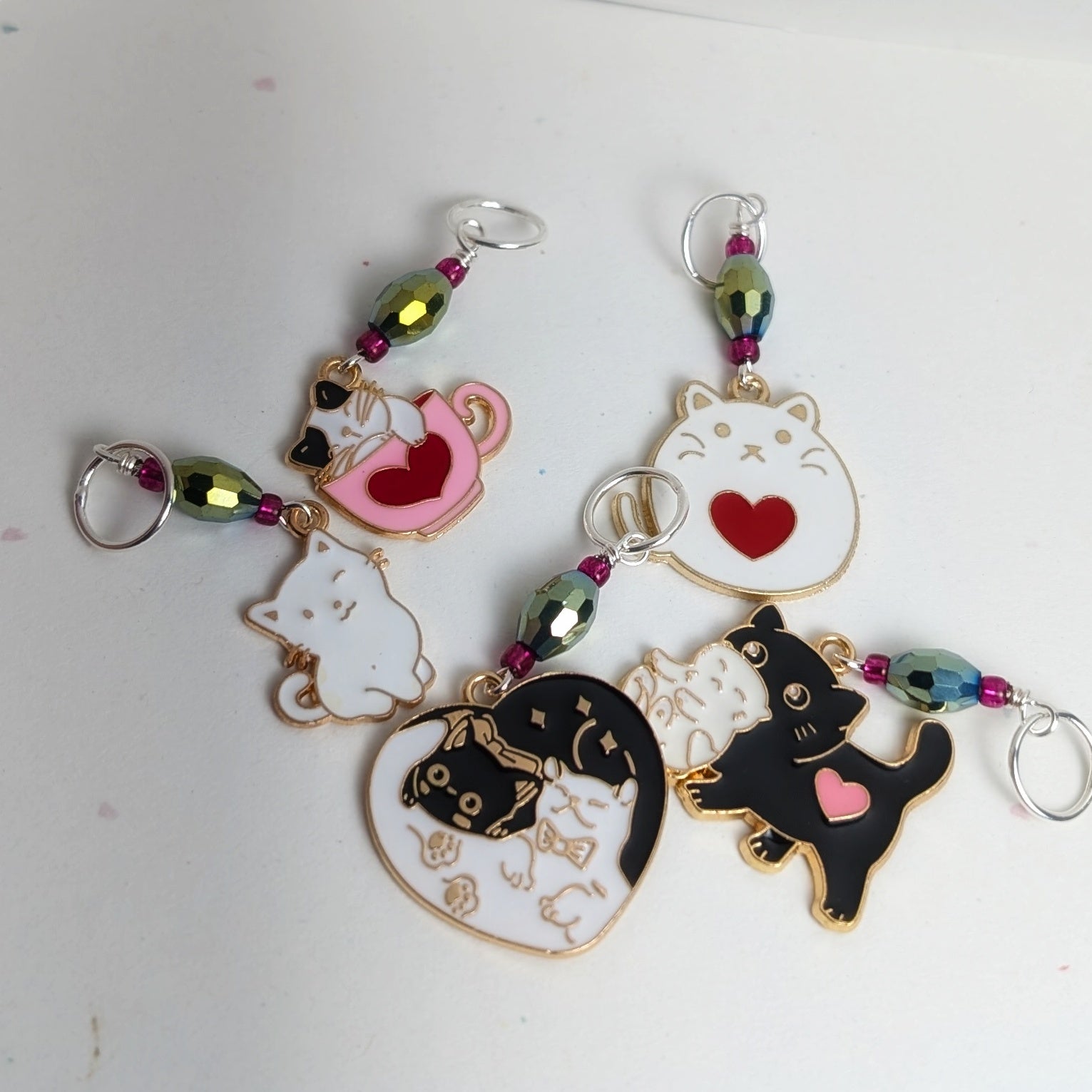 Cat-themed stitch markers with colorful beads on a white background