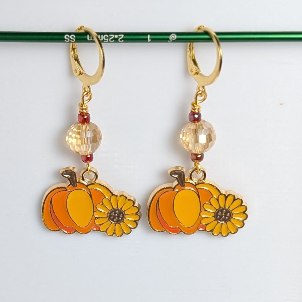 Pumpkin and sunflower earrings with gold hooks on a white background