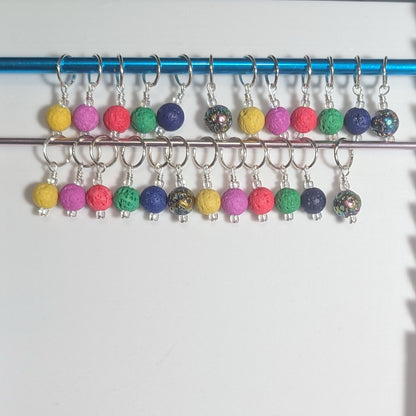 Colorful knit stitch markers on a metal rod against a white background