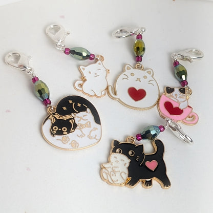 Set of cat-themed stitch markers with heart designs on a light background