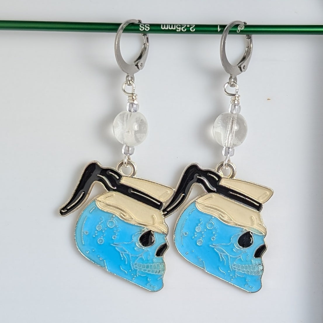 Pair of blue skull-shaped earrings with gold accents on a white background